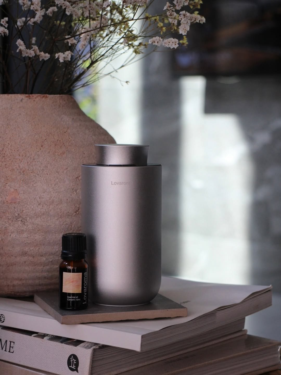 花器と本の上に置いたCore Diffuser Mini H11と精油